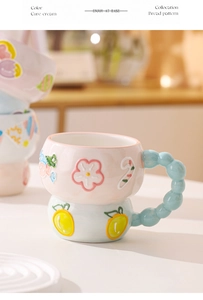 Detail of pink and blue relief ceramic mug with beaded handle and scalloped coaster