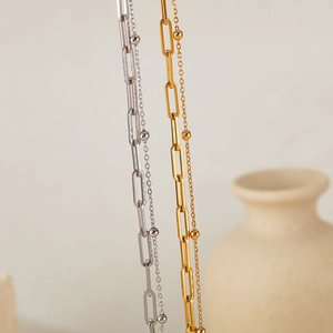 Detail view of gold and silver paperclip link necklaces with delicate metal beads
