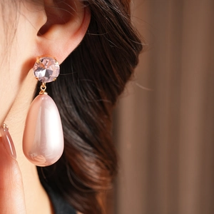 Gros plan de boucles d'oreilles gouttes roses avec cristaux portées par un mannequin