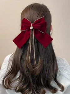 Dettaglio del fiocco per capelli in velluto bordeaux con perle e lunghe catene dorate