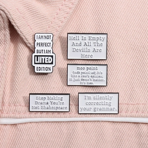 Macro detail of five enamel quote pins on light pink denim showing refined metal craftsmanship