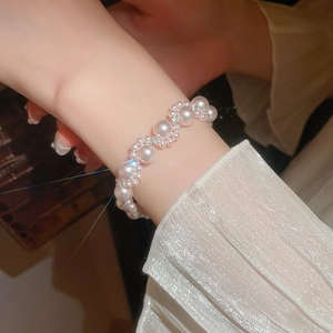 Detailed view of layered faux pearl bracelet with sparkling rhinestones on model wrist