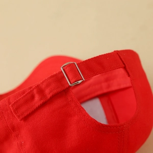 Detailed close-up of the adjustable metal buckle on a trendy red cotton baseball cap
