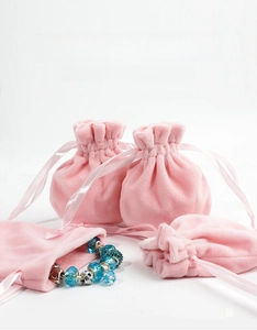 Pink plush drawstring pouch showing soft velvet texture and silk ribbon for jewelry storage