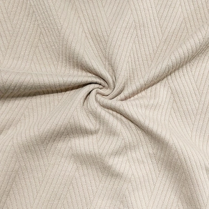 Détail macro du tissu en maille jacquard beige avec motif à chevrons pour ensemble homme
