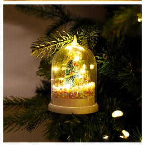 Detail of a glowing glass dome Christmas ornament with a miniature tree and LED lights
