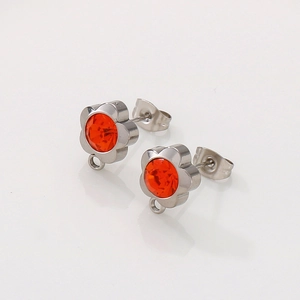 Detail of silver flower stud earrings with orange rhinestones and hanging jewelry loop
