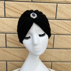 Detail of a black knitted headband featuring a vintage silver flower with a blue gemstone