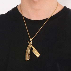 Close-up of a gold razor pendant on a twist chain worn by a male model in black t-shirt