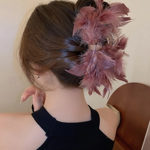 Close-up of elegant dusty rose feather hair claw clip on female model updo hairstyle