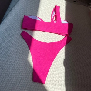 Close-up of pink textured bikini fabric with one-shoulder design and stylish side shadows