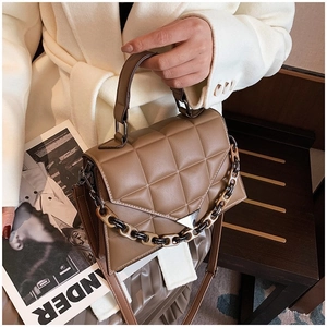 Detail of khaki quilted leather handbag with thick decorative chain and long shoulder strap
