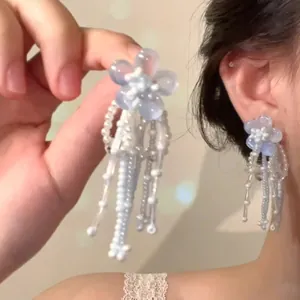 Detail of blue flower tassel earrings featuring frosted petals and delicate white pearls