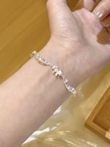 Bracelet nœud en argent avec zircons porté par un mannequin sur un fond chaleureux