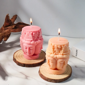 Dettaglio di candele Buddha accese rosa e arancio su base in legno zen
