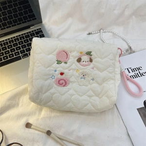 Close-up of heart-quilted cosmetic bag with cartoon embroidery and pink wrist strap