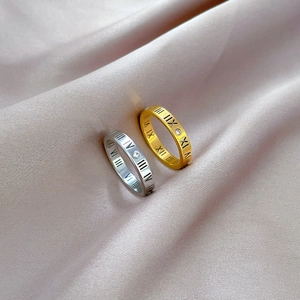 Macro shot of titanium steel rings with Roman numerals and diamond accents on silk