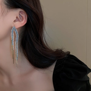 Close-up of model wearing silver tassel earrings with blue and clear rhinestones