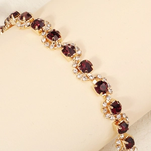 Macro shot of gold bridal hair comb with large burgundy crystals and clear rhinestones