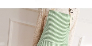 Detail of green striped cotton apron showing adjustable shoulder strap and large front pocket