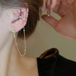 Detailed close-up of a golden butterfly ear cuff with sparkling zircon and pearl accents