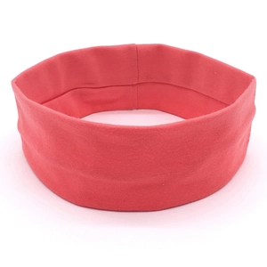 Close-up of coral pink elastic yoga headband showing soft knit fabric texture