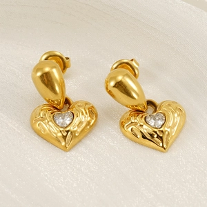 Macro detail of 18k gold plated hammered heart earrings with a clear round diamond inlay