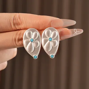 Detail of vintage silver teardrop earrings with flower pattern and blue stones
