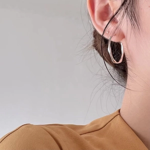 Close-up of model wearing stylish 925 sterling silver Mobius wave hoop earrings
