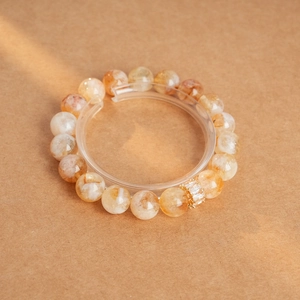 Détail macro du bracelet en perles de cristal jaune avec charms en zircon doré