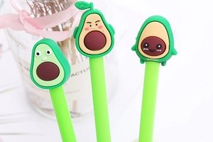 Three green pens with cartoon avocado tops in a soft natural light setting