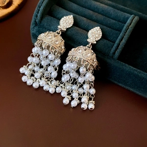 Detail of silver pearl tassel earrings with rhinestones on a dark green velvet box