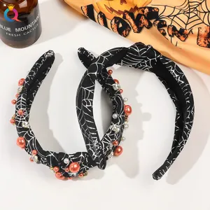Detail of Halloween headband with white spider web print, orange pearls and shiny rhinestones