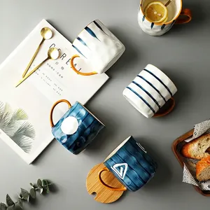 Japanese style ceramic mugs set with blue patterns, orange handles, and wood lids