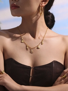Close-up of a model wearing a gold ocean-themed necklace with shell, seahorse and octopus charms
