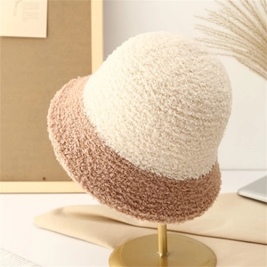 Chapeau bob d'hiver en peluche beige et camel posé sur un support doré