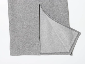 Close-up detail of grey knitted fabric texture and double-stitched side slit hem finish