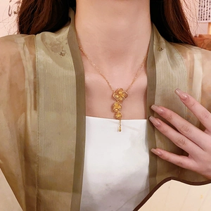 Detailed close-up of gold plated flower tassel necklace worn on a model neckline