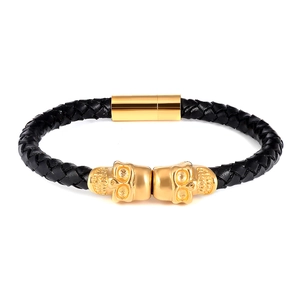 Close-up of black braided leather bracelet with gold skull accents and magnetic clasp