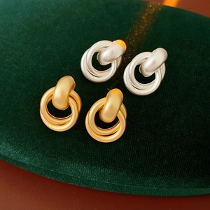 Macro detail of gold and silver matte double loop earrings on green velvet