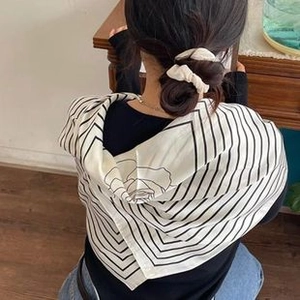 Detail of white striped cotton linen scarf with rose pattern worn as a hair accessory