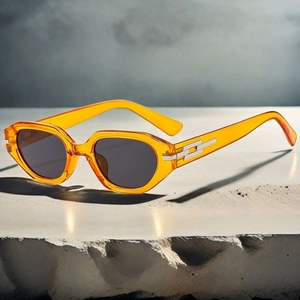 Detail view of retro geometric orange sunglasses on a textured grey stone surface