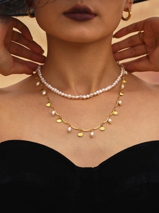 Close-up of double-layered baroque pearl necklace and golden shell pendant on a model