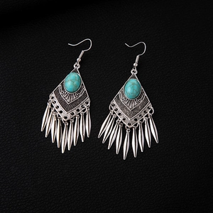 Detail of bohemian silver earrings with turquoise stones and vintage metal tassels
