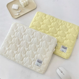 Detailed close-up of cloud-quilted laptop sleeves in cream and pale yellow colors