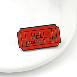 Red enamel movie ticket pin with HELL and 666 engraving on a white ceramic plate