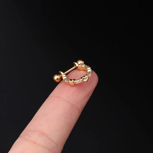 Macro view of a gold-plated heart-shaped cartilage stud with white cubic zirconia crystals
