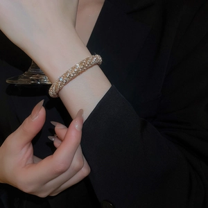 Close-up of gold-plated twisted bangle with pave crystals on a woman's wrist