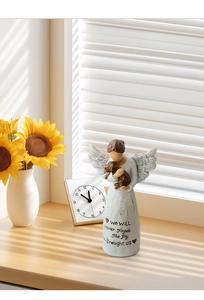 Detalle de figura de ángel con perro y texto conmemorativo en el vestido de resina