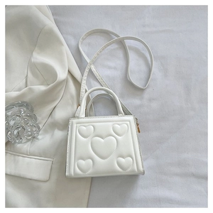 Détail du sac à main blanc gaufré de cœurs avec bandoulière et poignée élégante